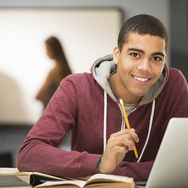 IMAGE: Teenager sitting at laptop and smiling