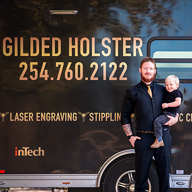 IMAGE: Gilded Holster owner John with son in front of trailer