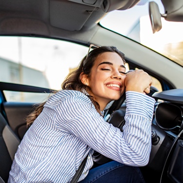 a happy woman holding on to her steering wheel