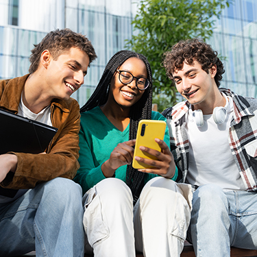 IMAGE: Three friends looking at phone together smiling