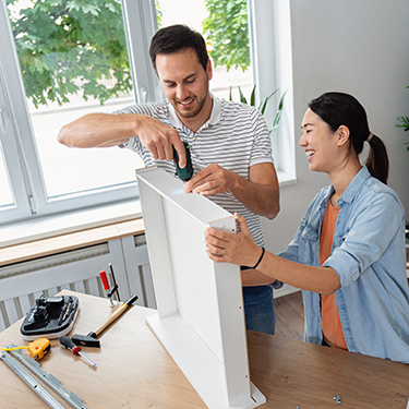 IMAGE: Couple smiling while putting together kitchen drawer 