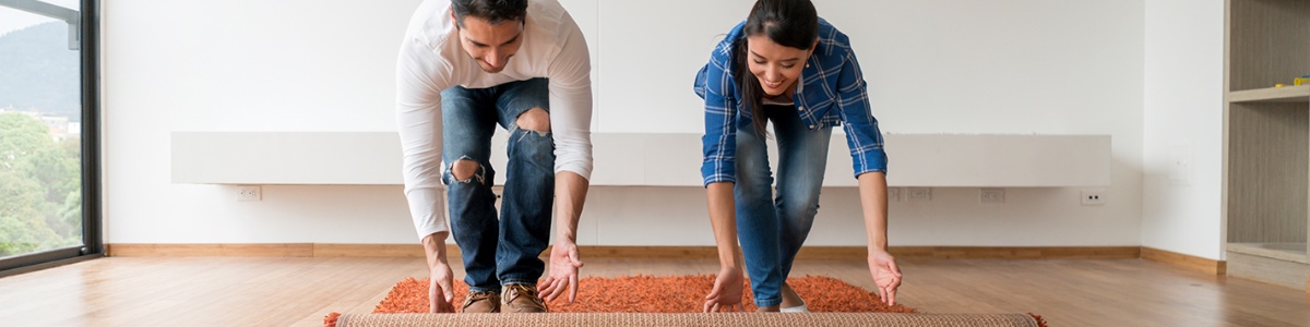 couple rolling out a rug for their new home