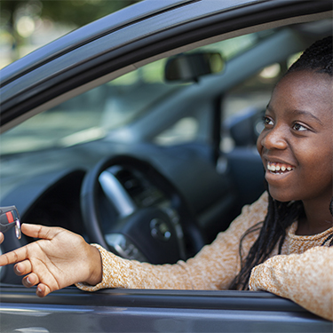 IMAGE: Smiling teen driver behind the wheel of a car being handed keys