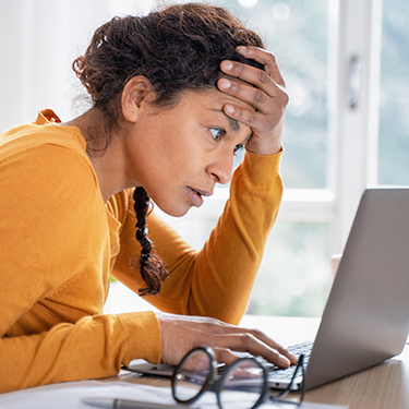 IMAGE: woman looking closely at a laptop with a worried expression