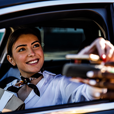 IMAGE: Smiling woman using phone to pay at a drive-thru