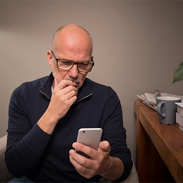 IMAGE: Man looking concerned holding smartphone