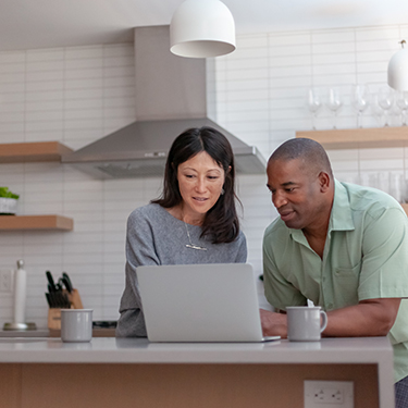 IMAGE: Couple looking at laptop in kitchen