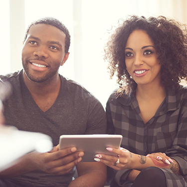 IMAGE: Couple holding tablet and smiling talking to an insurance agent