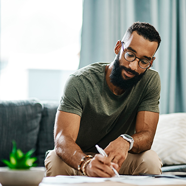 IMAGE: Man sitting on couch writing on paper