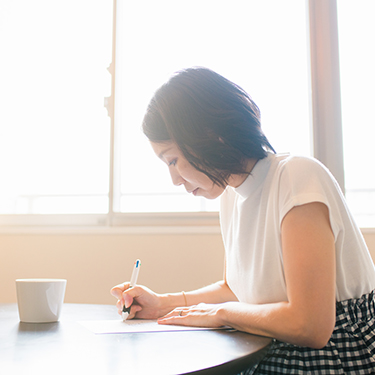 IMAGE: Woman sitting at a table signing documents