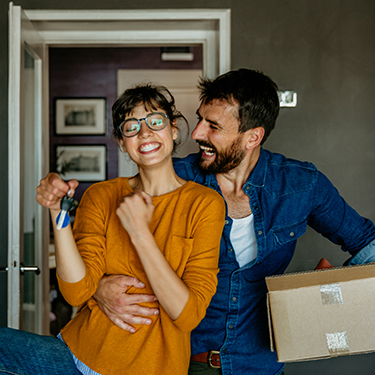 IMAGE: Happy couple moving into a house with woman holding keys