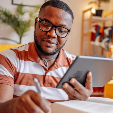 IMAGE: Man holding tablet and writing at a desk