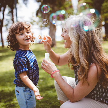 IMAGE: Grandmother blowing bubble for grandkid