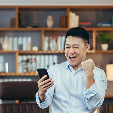IMAGE: Man holding phone pumping fist and excited