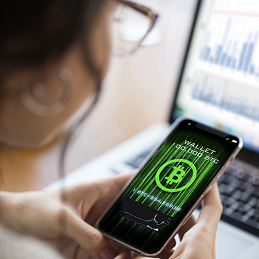 IMAGE: Woman holding a phone with a bitcoin wallet displayed on the screen