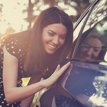 a woman smiling touching her new car