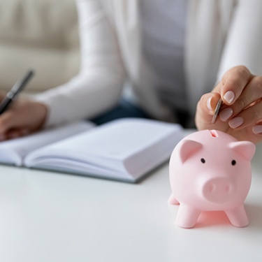 a hand putting coins in a piggy bank