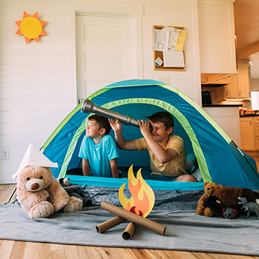 IMAGE: Boys in living room in tent with toy telescope and play fire make of paper towel tubes and construction paper.