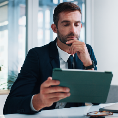 IMAGE: Man in a suit inside an office looking concerned at tablet