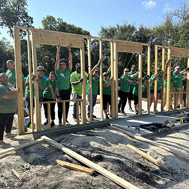 IMAGE: Texell team members holding up framing for house at Habitat for Humanity