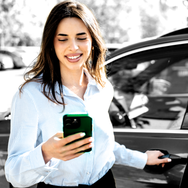 IMAGE: Woman holding phone and smiling while pulling a car door handle