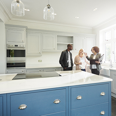 IMAGE: Couple talking with realtor inside kitchen of new home