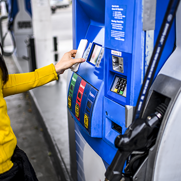 IMAGE: Person holding phone up to gas pump to pay.