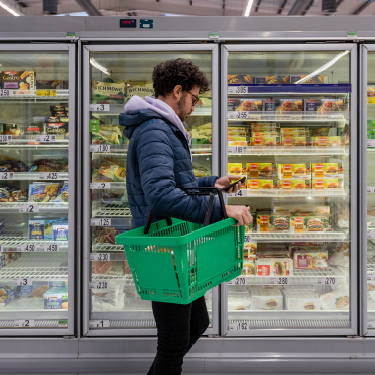 IMAGE: Man holding phone while shopping in a grocery store
