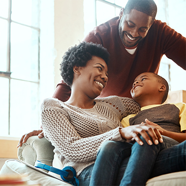 IMAGE: Mom with boy on her lap and dad looking down on them smiling