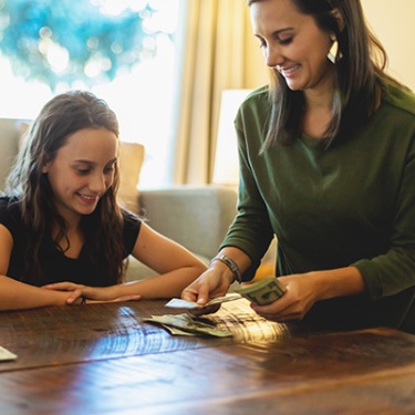 a mother counting money in front of her daughter