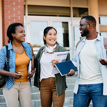 IMAGE: Three college students laughing and walking outside of a building