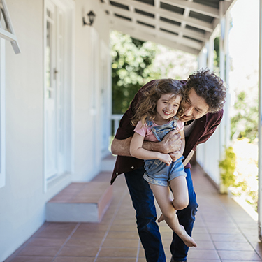 IMAGE: Dad carrying daughter smiling on front porch