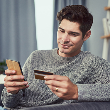 IMAGE: Man holding credit card and phone smiling