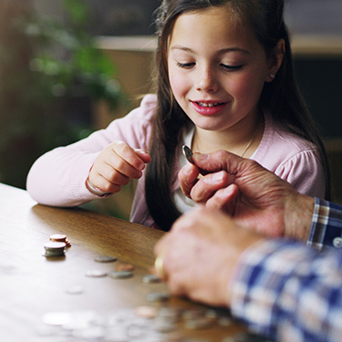 IMAGE: Older person handing a coin to a young girl