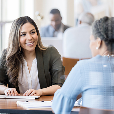 IMAGE: Woman smiling at the computer talking to a member