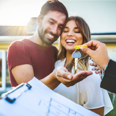 IMAGE: Couple smiling and being handed keys to new home