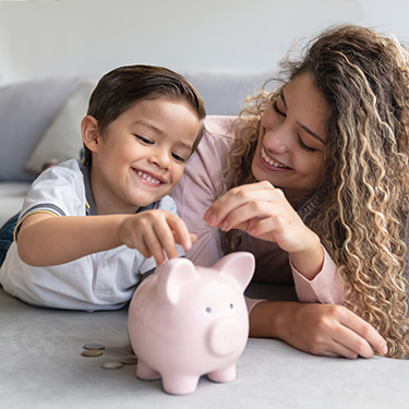IMAGE: Mom with kid putting coins into piggy bank