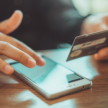 IMAGE: Person holding credit card and entering information into a cell phone