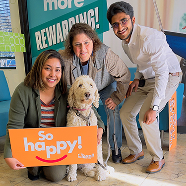 IMAGE: Texell Home Loans employees with client and poodle in lobby with a sign that says So happy!