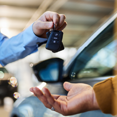 IMAGE: Person handing car keys to another person at a dealership