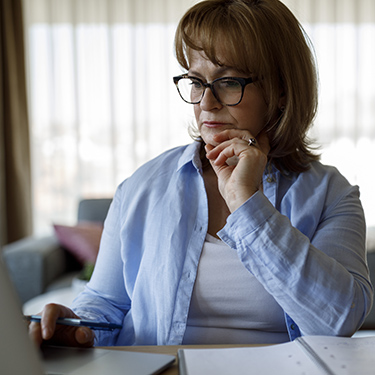 IMAGE: woman working on a laptop with a worried exprssion