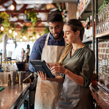IMAGE: Man and woman working in a restaurant looking at a tablet