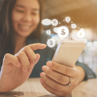 IMAGE: Person holding phone and smiling with dollar sign icons above phone