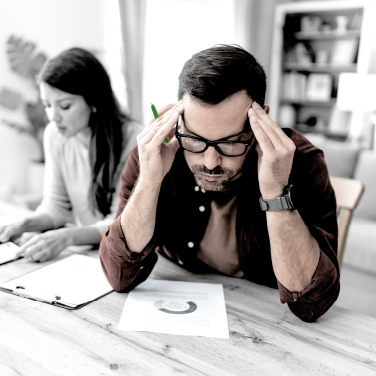 IMAGE: Man sitting next to a woman inside a house and studying his credit score on paper.