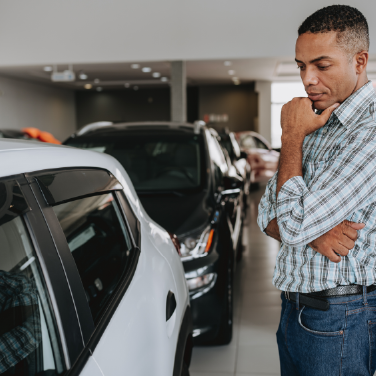 IMAGE: Man studying a white vehicle in a car dealership