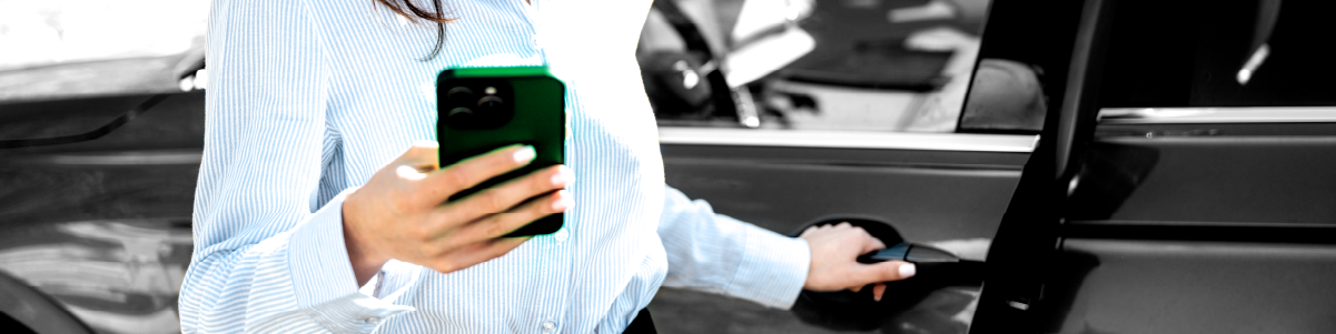IMAGE: Woman holding phone and smiling while pulling a car door handle