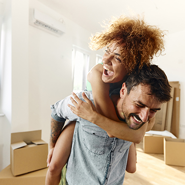IMAGE: Couple laughing inside new home with boxes in background