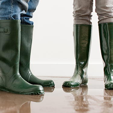 IMAGE: Two people standing in rain boots inside a home