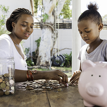 IMAGE: Mother and child counting change with piggy bank and jar