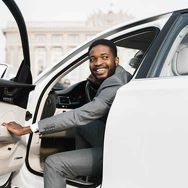 Man smiling while getting into a brand new car.